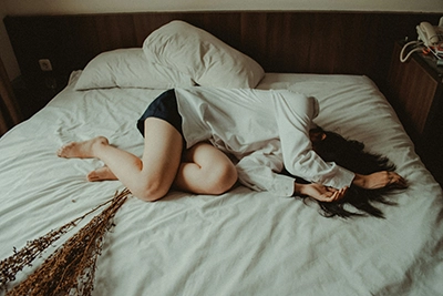 Mujer tumbada en una cama deshecha