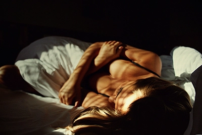 Mujer tumbada en una cama en penumbra